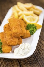 Some fried Fish Sticks (selective focus) on an old wooden table