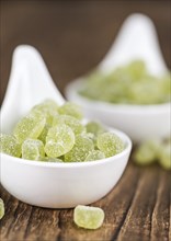 Wooden table with sour gummy candy (apple taste) as detailed close-up shot