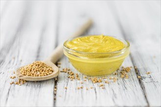 Fresh made Mustard on a vintage background (close-up shot)