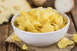 Homemade Cheese and Onion Potato Chips on vintage background (selective focus, close-up shot)