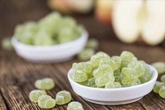 Sour gummy candy (apple taste) on an old wooden table (selective focus)