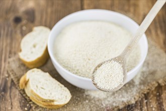 Wooden spoon with Breadcrumbs (close-up shot, selective focus) on an old wooden table