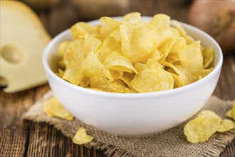 Cheese and Onion Potato Chips on an old wooden table as detailed close-up shot (selective focus)