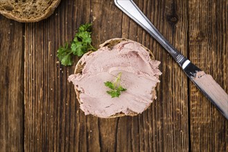 Roll with Liverwurst (German cuisine) on an old wooden table as detailed close-up shot (selective