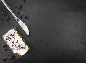 Slate slab with cream cheese and fresh cress on a slice of wholemeal bread (close-up shot,