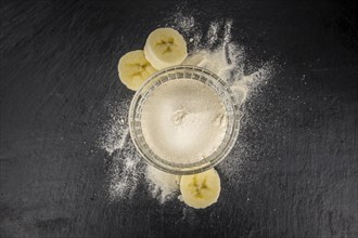 Portion of Banana Powder as detailed close up shot on a slate slab, selective focus