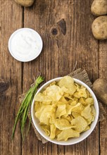 Fresh made Potato Chips with Sour Cream taste on a vintage background (close-up shot)