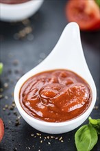 Some fresh made Tomato Ketchup on a vintage slate slab (selective focus, close-up shot)