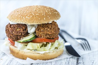 Fresh madeFalafel Burger on wooden background (close-up shot, selective focus)