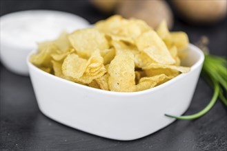 Some Potato Chips with Sour Cream taste on a slate slab (close-up shot, selective focus)