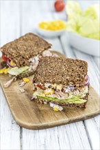 Old wooden table with Tuna sandwich (on wholemeal bread, selective focus)