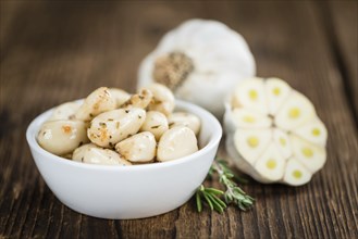 Marinated Garlic on an old wooden table as detailed close-up shot (selective focus)