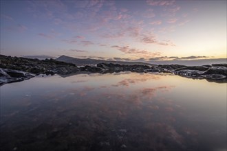 View of the sunrise over the Atlantic. Dreamlike clouds and a bay with a stone beach on a volcanic