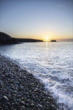 View of the sunrise over the Atlantic. View over a stone beach on a volcanic island. Cold lava