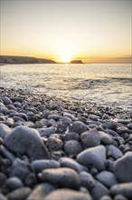 View of the sunrise over the Atlantic. View over a stone beach on a volcanic island. Cold lava