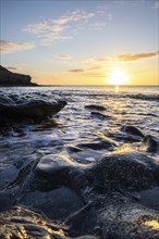 View of the sunrise over the Atlantic. View over a stone beach on a volcanic island. Cold lava