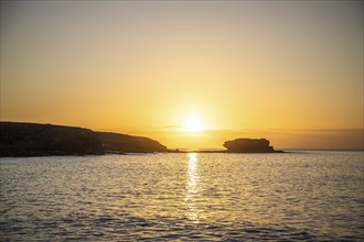 View of the sunrise over the Atlantic. View over a stone beach on a volcanic island. Cold lava