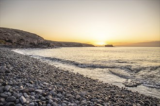 View of the sunrise over the Atlantic. View over a stone beach on a volcanic island. Cold lava