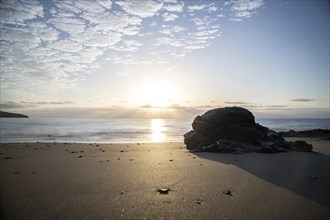 View of the sunrise over the Atlantic. Dreamlike clouds and a bay with a stone beach on a volcanic