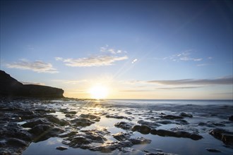 View of the sunrise over the Atlantic. View over a stone beach on a volcanic island. Cold lava