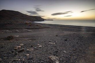 View of the sunrise over the Atlantic. A coastline and a bay with a rocky beach on a volcanic