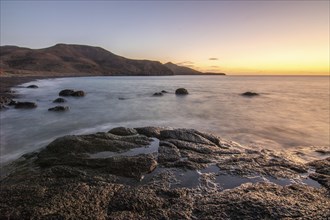 View of the sunrise over the Atlantic. View over a stone beach on a volcanic island. Cold lava