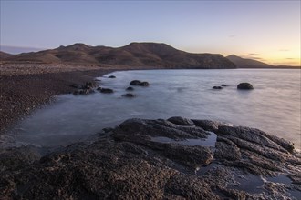 View of the sunrise over the Atlantic. View over a stone beach on a volcanic island. Cold lava