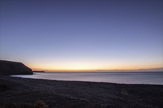 View of the sunrise over the Atlantic. A coastline and a bay with a rocky beach on a volcanic