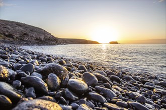 View of the sunrise over the Atlantic. View over a stone beach on a volcanic island. Cold lava