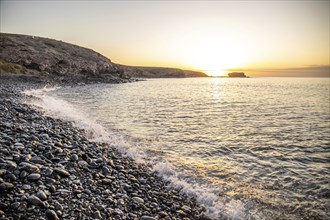 View of the sunrise over the Atlantic. View over a stone beach on a volcanic island. Cold lava