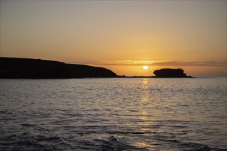 View of the sunrise over the Atlantic. View over a stone beach on a volcanic island. Cold lava