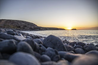 View of the sunrise over the Atlantic. View over a stone beach on a volcanic island. Cold lava