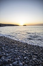 View of the sunrise over the Atlantic. View over a stone beach on a volcanic island. Cold lava