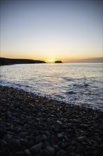 View of the sunrise over the Atlantic. View over a stone beach on a volcanic island. Cold lava