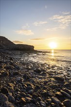 View of the sunrise over the Atlantic. View over a stone beach on a volcanic island. Cold lava