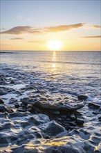 View of the sunrise over the Atlantic. View over a stone beach on a volcanic island. Cold lava