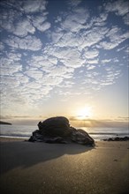 View of the sunrise over the Atlantic. Dreamlike clouds and a bay with a stone beach on a volcanic