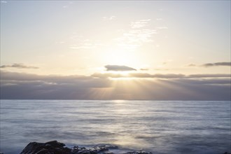 View of the sunrise over the Atlantic. Dreamlike clouds and a bay with a stone beach on a volcanic