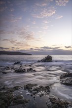 View of the sunrise over the Atlantic. Dreamlike clouds and a bay with a stone beach on a volcanic