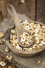 Portion of freshly chopped Hazelnuts on an old wooden table as detailed close up shot (selective