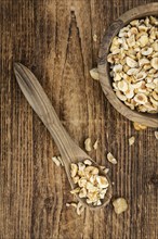 Portion of freshly chopped Hazelnuts on an old wooden table as detailed close up shot (selective