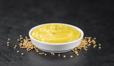 Fresh made Mustard on a vintage background (close-up shot)