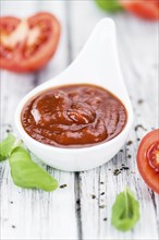 Tomato Ketchup on an old wooden table as detailed close-up shot (selective focus)