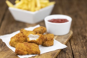 Vintage wooden table with fresh made Chicken Nuggets (close-up shot, selective focus)