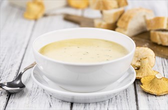 Chanterelle Soup as high detailed close-up shot on a vintage wooden table, selective focus