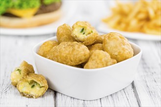 Cheese Nuggets as high detailed close-up shot on a vintage wooden table (selective focus)