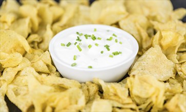 Potato Chips (Sour Cream taste) on a vintage background as detailed close-up shot (selective focus)