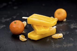 Portion of fresh homemade Tangerine Popsicles (close-up shot, selective focus) on a vintage