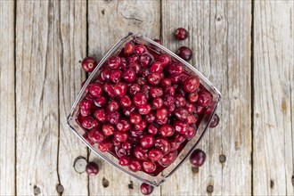 Old wooden table with fresh Preserved Cranberries (close-up shot, selective focus)