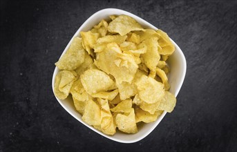 Potato Chips (Sour Cream taste) on a vintage background as detailed close-up shot (selective focus)